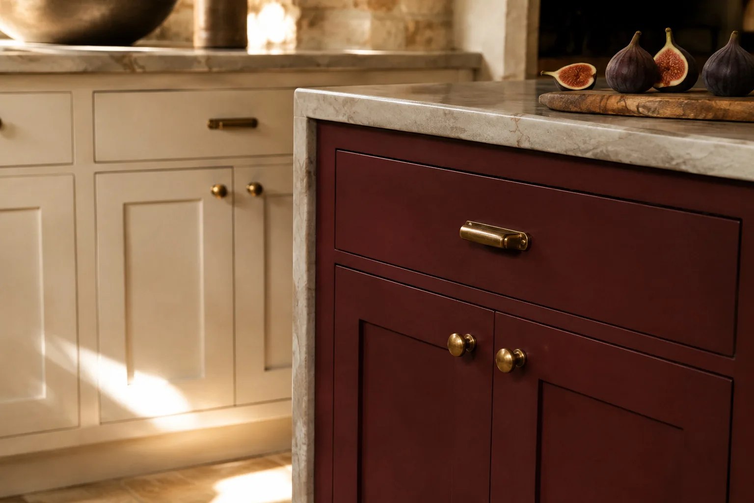 A deep oxblood-red cabinet run with brass hardware beneath a stone countertop